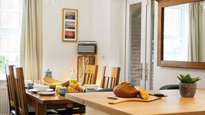 A dining area with a wooden table set for breakfast, including croissants and a loaf of bread.