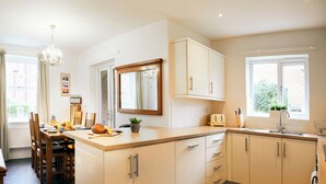 A modern kitchen with a central island, wooden cabinets, and a large mirror.