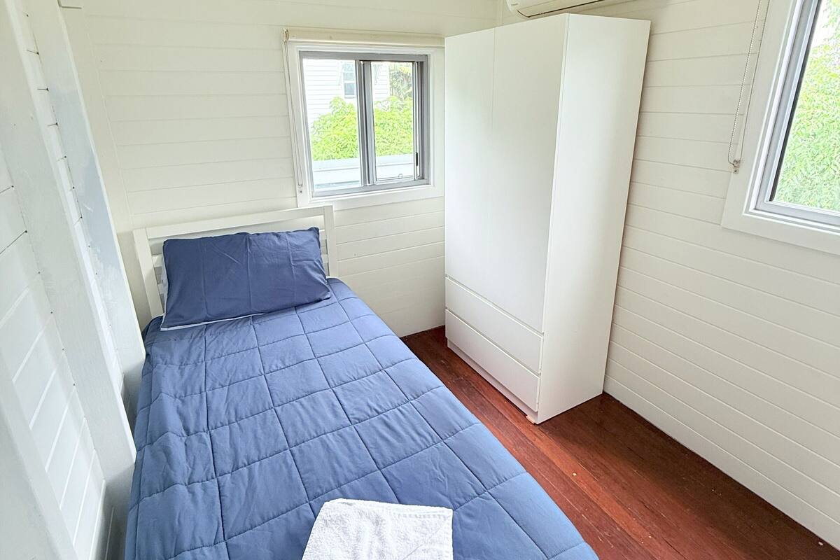 Une chambre à coucher avec un lit, une fenêtre et une armoire blanche.