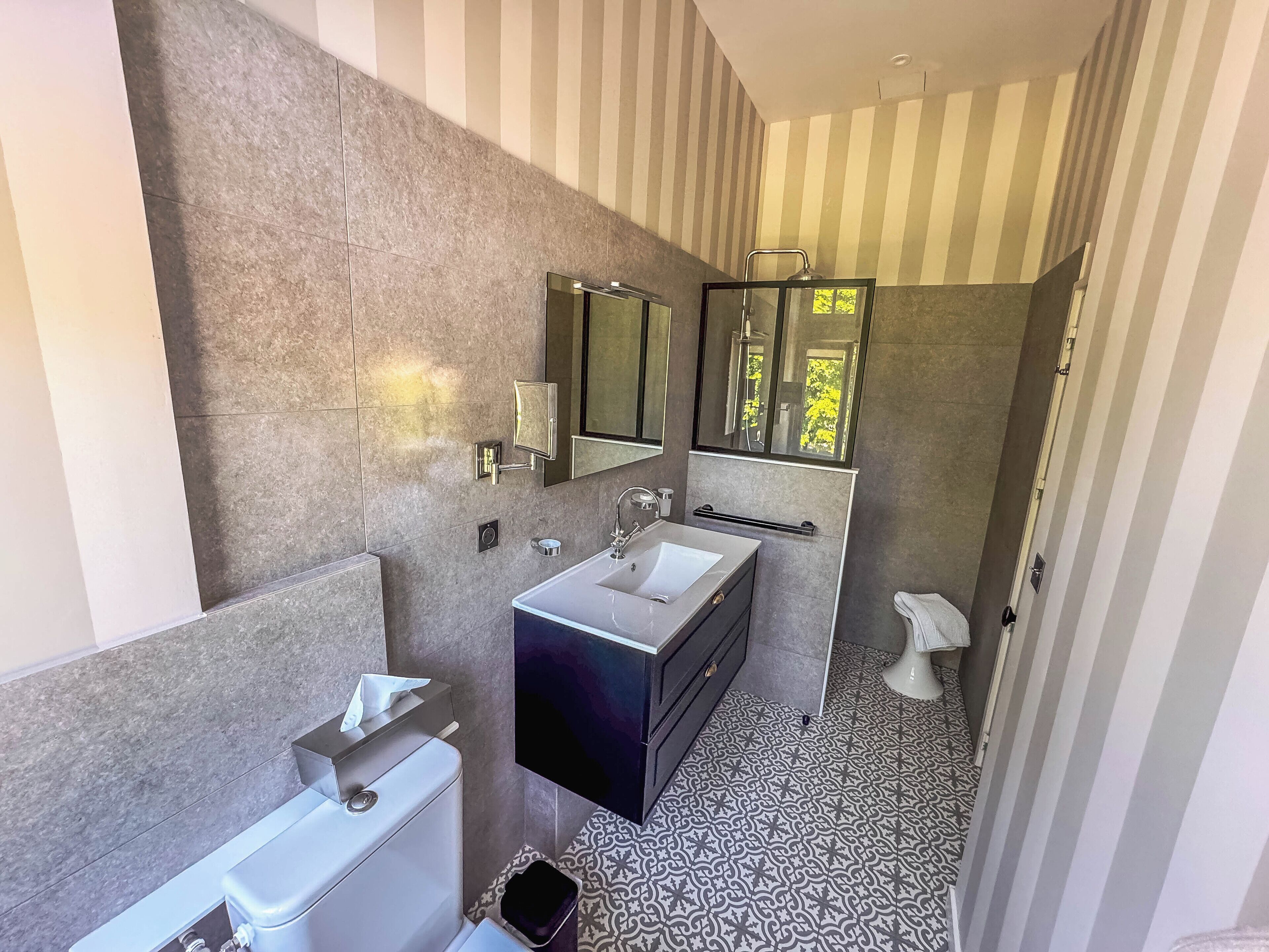A modern bathroom with a large mirror, a vanity with a sink, and a toilet.
