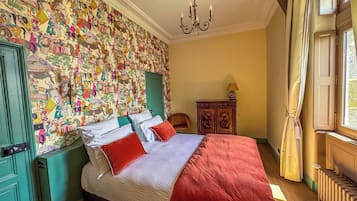 Un dormitorio con una cama grande, una mesita de noche verde, un armario de madera y una pared con un mural colorido.