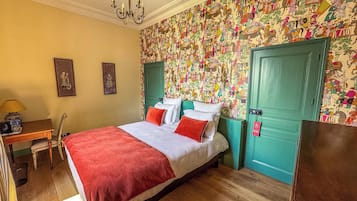 Een slaapkamer met een bed, een bureau, een stoel en een groene deur.