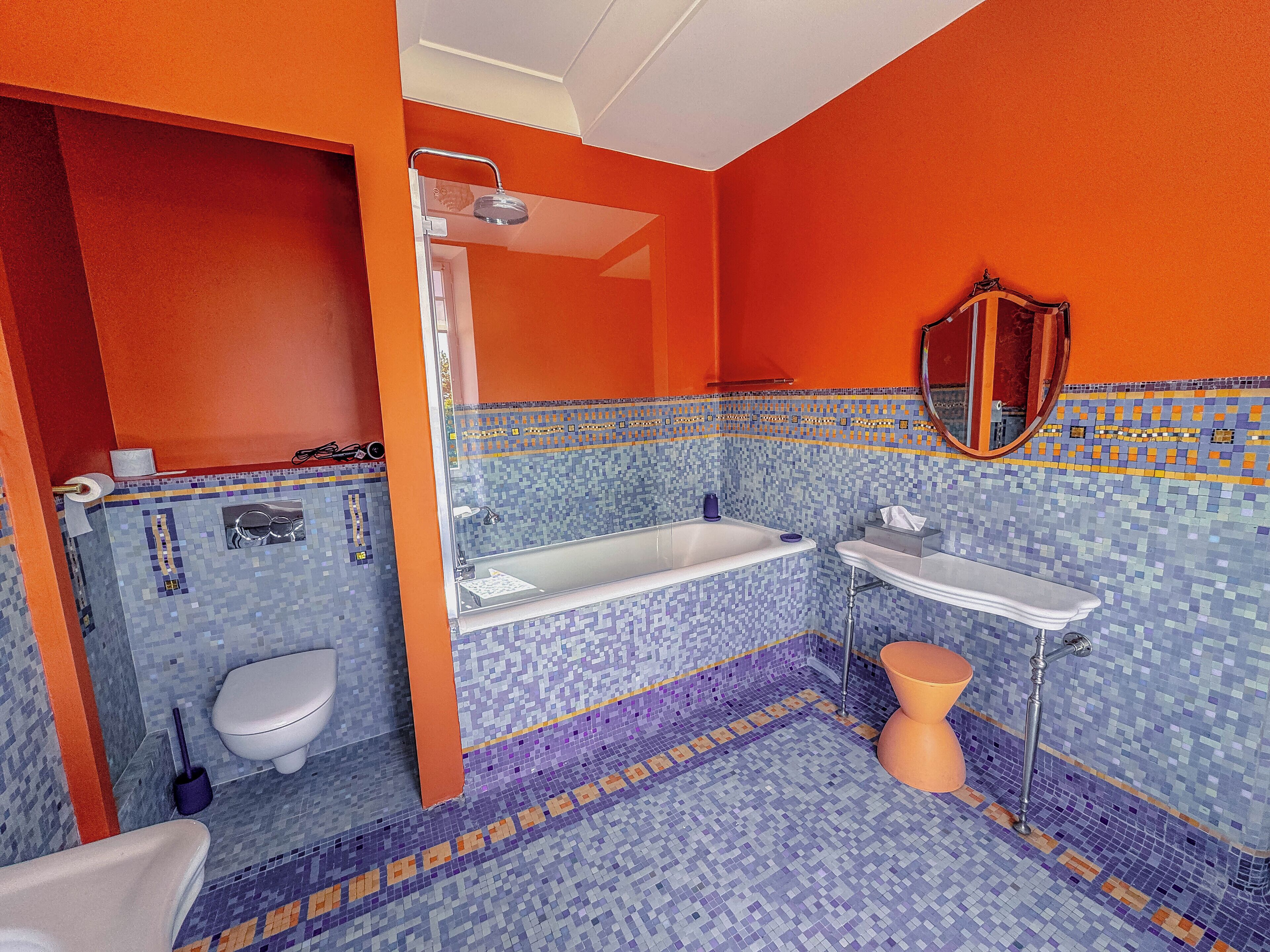 Une salle de bain avec un sol carrelé en mosaïque, une baignoire, des toilettes et un lavabo.