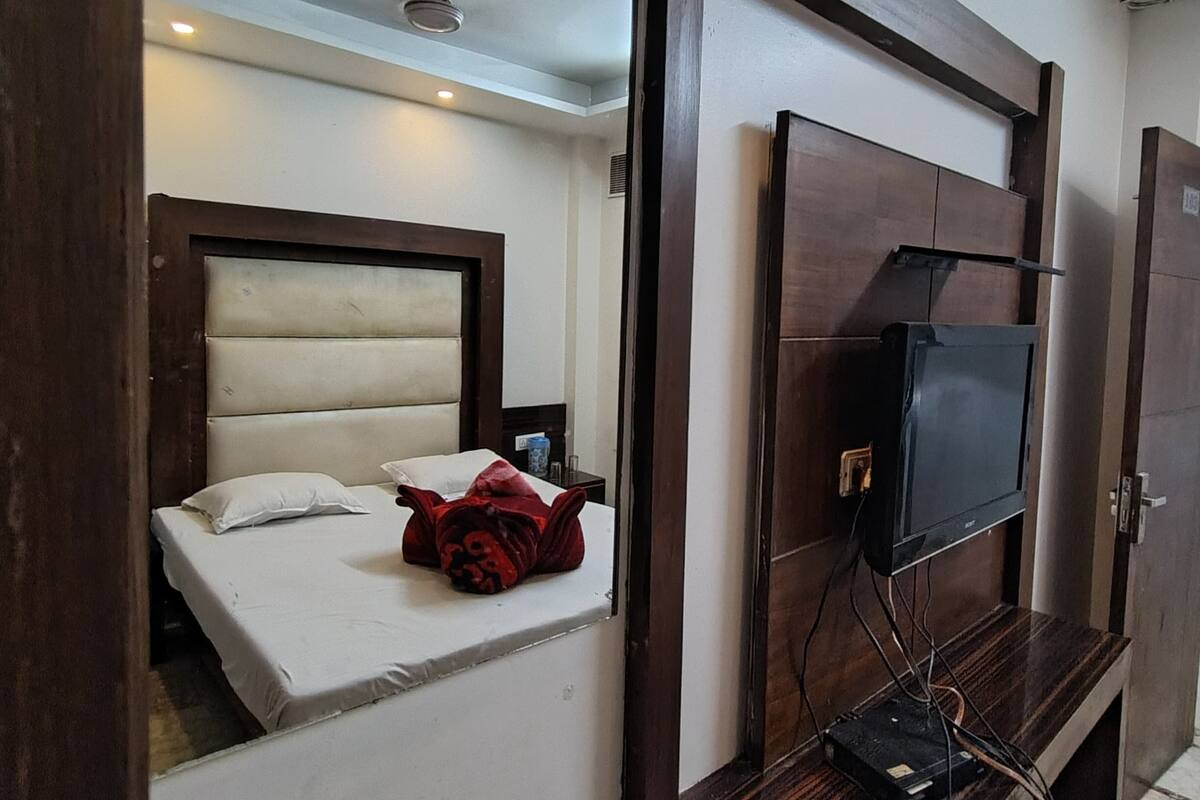 A hotel room with a bed, a television, and a mirror.