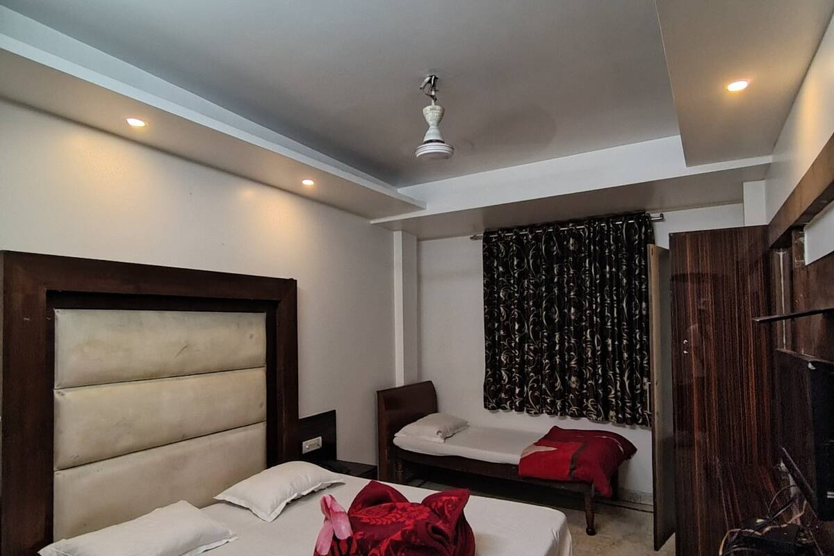 A hotel room with two beds, a ceiling fan, and a large mirror.