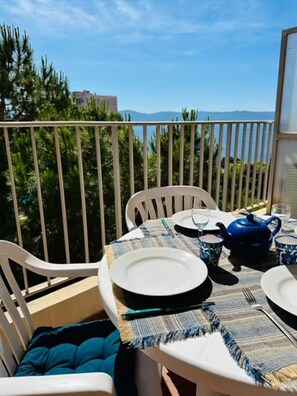 A balcony with a table set for two, featuring a blue teapot, white plates, and a striped tablecloth. - Oceanfront Getaway – Terrace, View & Free Parking (Ajaccio)