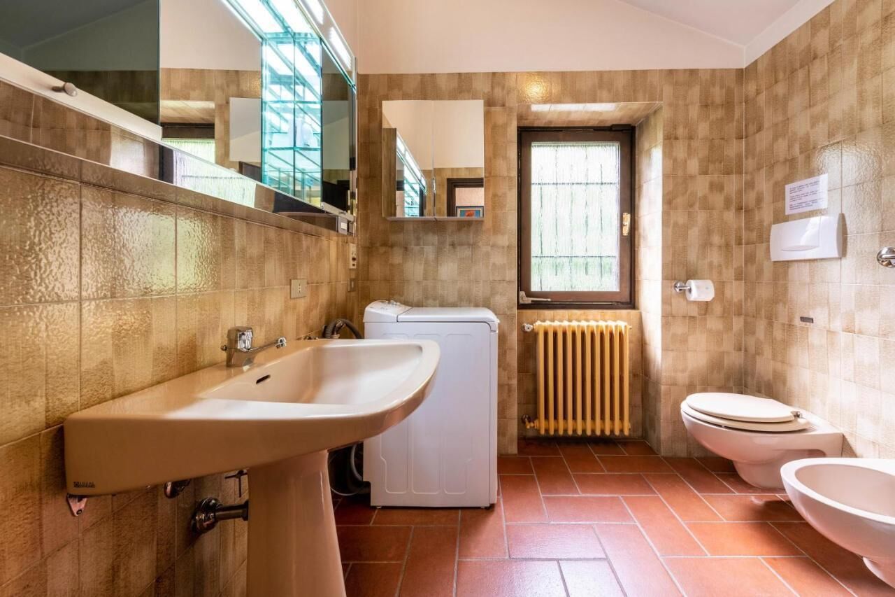 A bathroom with a sink, a toilet, a washing machine, and a radiator.