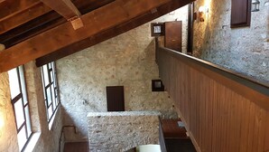 A stone-walled stairwell with wooden railings and a wooden ceiling beam. - Antico Fienile Belvedere (Gardone Riviera)