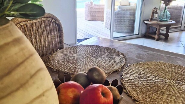 A living room with a wicker sofa, a woven coffee table, and a fruit bowl.