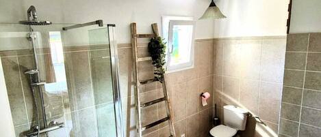 Un baño con ducha de vidrio, inodoro y lavamanos.