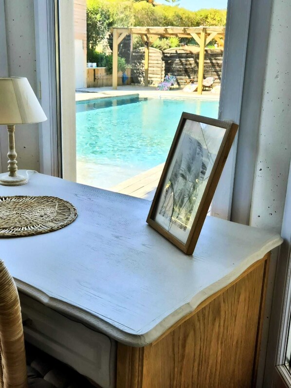 Una habitación con vista a una piscina, un cuadro enmarcado, una lámpara y un posavasos tejido.