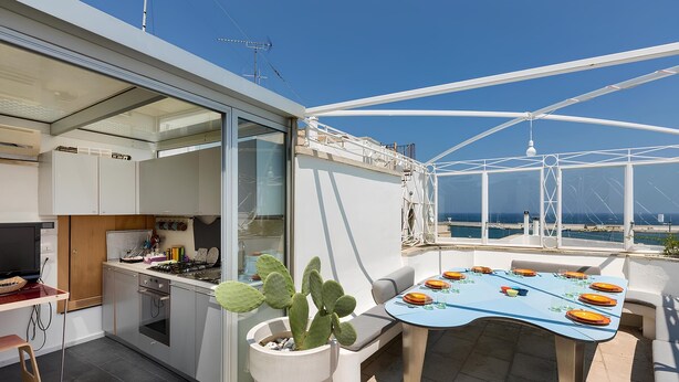Eine moderne Küche mit Essbereich, einer großen Sukkulente und Blick auf das Meer.