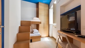Ein kleines Zimmer mit Bett, Fernseher und Kleiderschrank.