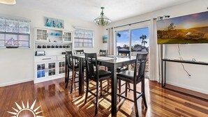 A dining area with a wooden table and chairs, a chandelier, and a large window with a view of a landscape.