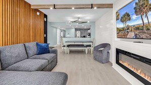 A modern living room with a gray sofa, a dining area with a white table, and a fireplace. - The Sands at Ocean Reef (Myrtle Beach)