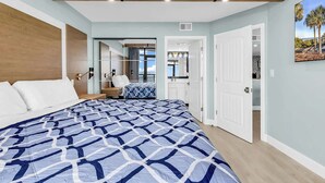 A bedroom with a large bed, a walk-in closet, and a bathroom with a large mirror. - The Sands at Ocean Reef (Myrtle Beach)