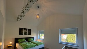 Un dormitorio con cama, cuna, mesita de noche y ventana con persianas.