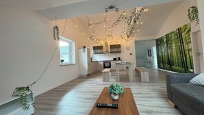 Una sala de estar moderna con una mesa de centro de madera, un sofá gris y una cocina al fondo.