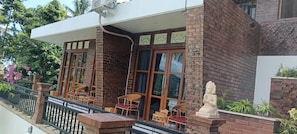 A building with a brick facade, large windows, and outdoor seating with chairs and tables. - Cempaka Homestay Sidemen  (Sidemen)