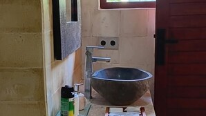 Ett badrum med en vit toalett, ett stort handfat, ett fönster och en dörr.