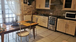Una cocina con paredes de piedra, armarios de madera, una mesa de comedor con sillas, una estufa y un microondas.