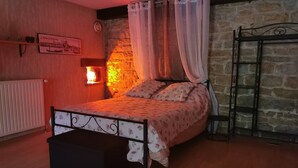 Un dormitorio acogedor con cama, mesita de noche, calentador de pared y pared de piedra.