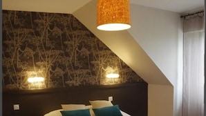 Een slaapkamer met een bed, een donker hoofdbord, twee wandlampen en een hanglamp.
