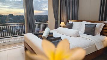 A hotel room with a large bed, a view of the city, and a balcony.