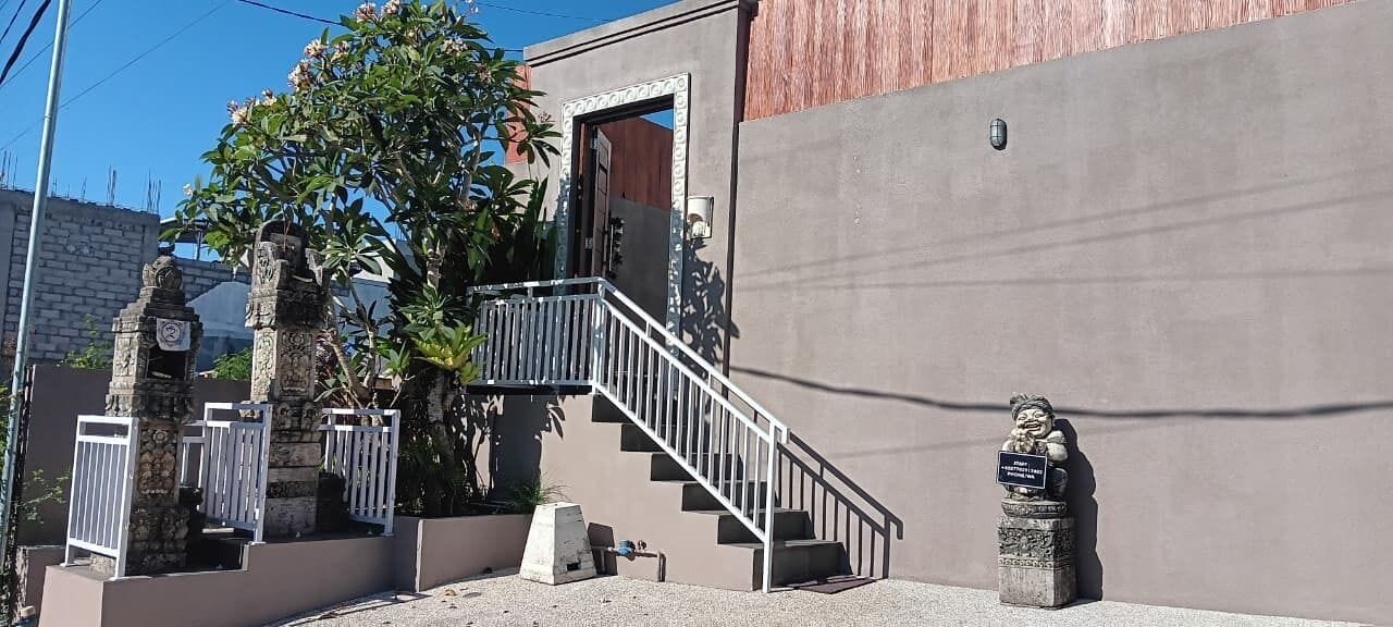 Un edificio con fachada de concreto, una escalera de metal y una pequeña estatua.