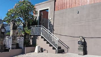 Un edificio con fachada de concreto, una escalera de metal y una pequeña estatua.