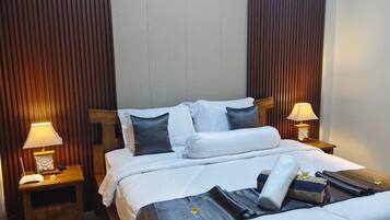 Habitación de hotel con una cama, dos lámparas de noche, aire acondicionado instalado en la pared y un cabecero de madera.