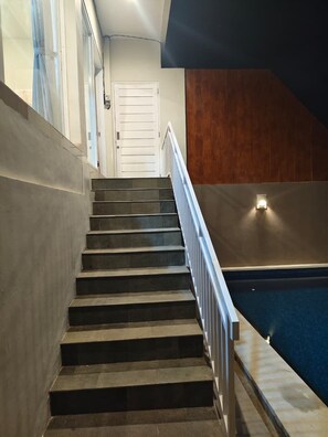 A staircase leading to a door, a pool area, and a wall with a light fixture. - Sarining 2BR Villa with Pool (Ungasan)