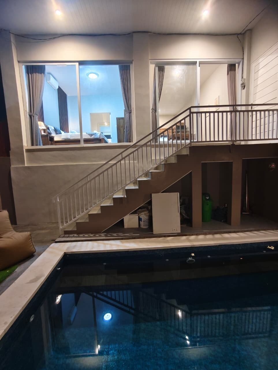 Una piscina con una escalera que sube a un balcón.