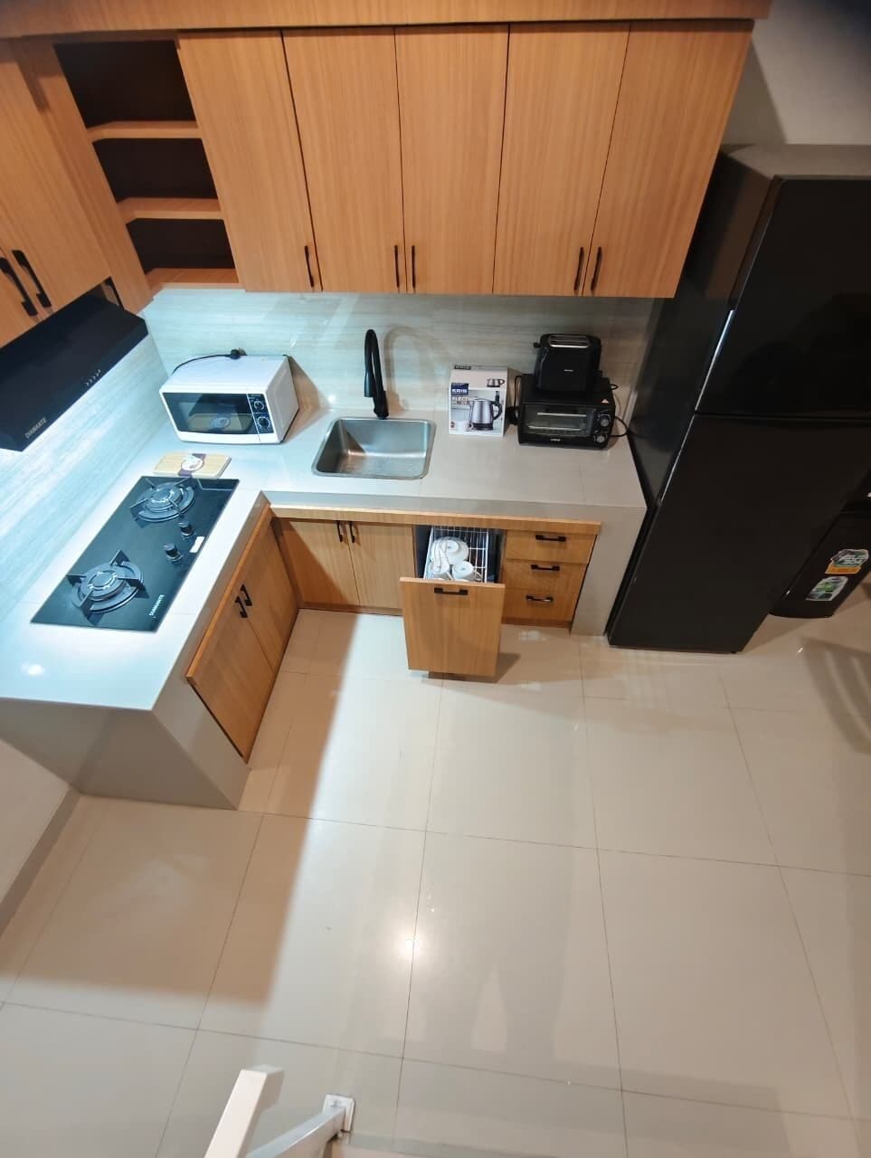 Una cocina con armarios de madera, estufa a gas, microondas, tostadora y refrigerador.