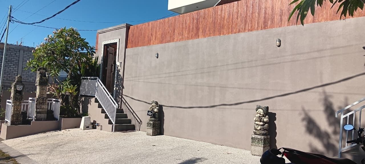 A building with a concrete facade, a staircase, and two stone statues.