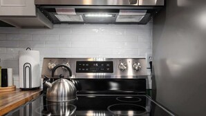Une cuisine moderne équipée d’une cuisinière en acier inoxydable, d’une bouilloire et d’un grille-pain.