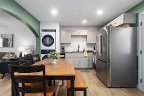 A compact kitchen with a dining area, a washing machine, and a refrigerator.