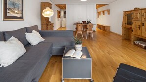 A modern living room with a grey sofa, a small table with a book, and wooden cabinets.