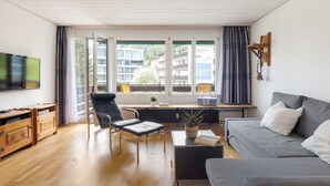 A modern living room with a sofa, a TV, a desk, and a chair.