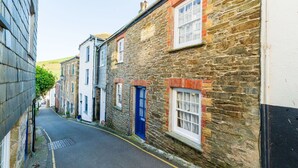 Une rue étroite bordée de bâtiments en pierre, où se côtoient des immeubles d’habitation et des locaux commerciaux.