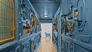 A narrow hallway with ornate blue walls and a wooden floor, leading to a room with a blue chair and a white wall. - Modern unit near Churchill Downs and Expo Center! (Louisville)