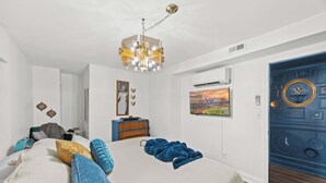 A bedroom with a large bed, a dresser, a chair, a blue door, and a chandelier. - Modern unit near Churchill Downs and Expo Center! (Louisville)