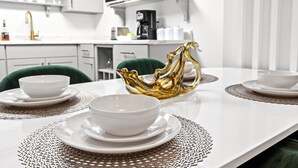 A modern kitchen with white cabinetry, a green chair, and a decorative golden bowl on the table. - Modern unit near Churchill Downs and Expo Center! (Louisville)