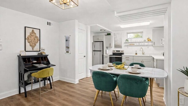 A modern kitchen with white cabinets, a built-in oven, and a stainless steel refrigerator. - Modern unit near Churchill Downs and Expo Center! (Louisville)