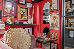 Une pièce avec un mur rouge, une affiche encadrée représentant un chien, une bouteille de whisky Old Forester et un certificat encadré.