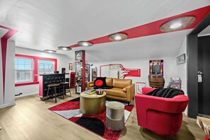 Un salon moderne aux couleurs rouge et blanche, avec un canapé en cuir, un fauteuil rouge, une table basse et un tapis rouge.