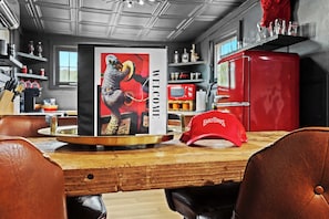 A kitchen with a vintage red refrigerator, a framed welcome sign, and a red cap on the table.