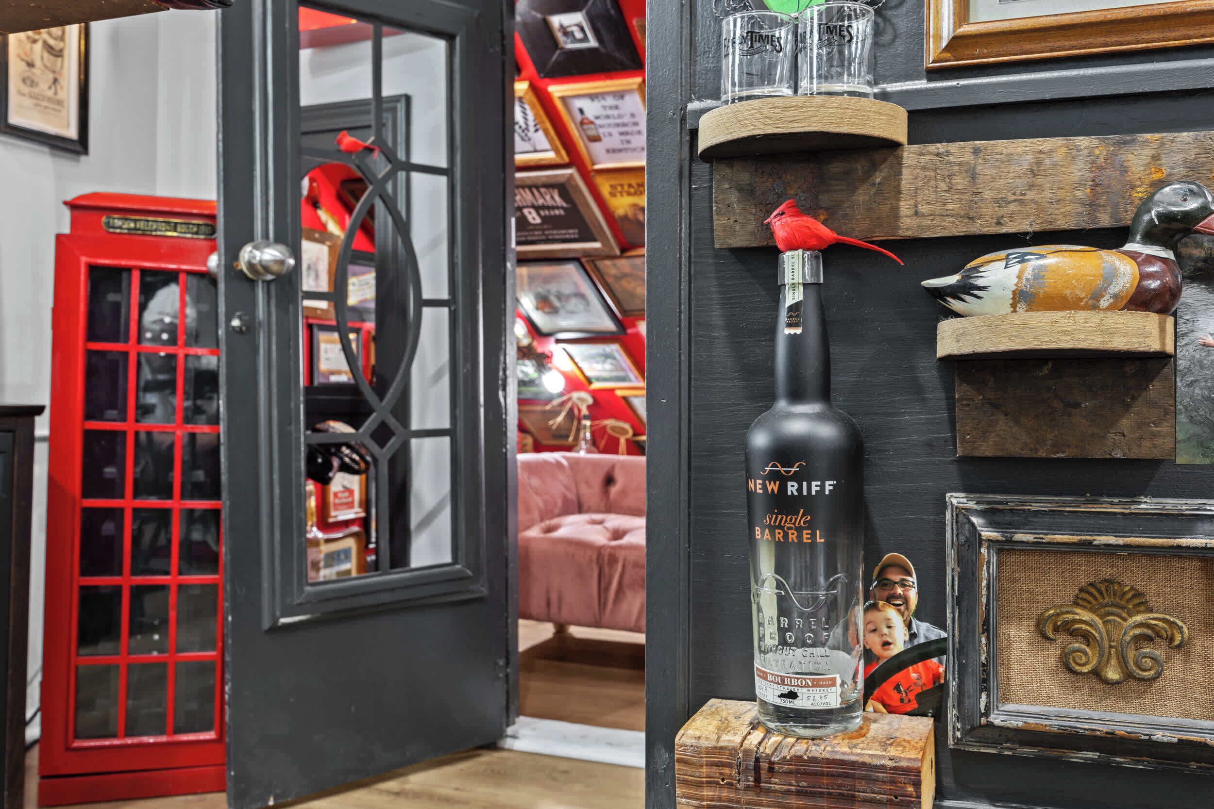 A room with a red telephone booth, a bottle of New York single barrel bourbon, and decorative items on shelves.