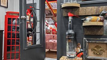 A room with a red telephone booth, a bottle of New York single barrel bourbon, and decorative items on shelves.