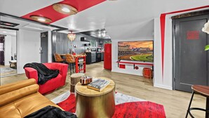Ein modernes Wohnzimmer mit rotem und weißem Farbdesign, einem großen Flachbildfernseher und einer Küchenzeile im Hintergrund.